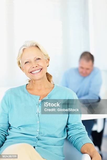 Bonita Mulher Sorridente Com Um Homem No Fundo - Fotografias de stock e mais imagens de 50 Anos - 50 Anos, 55-59 anos, 60-64 anos