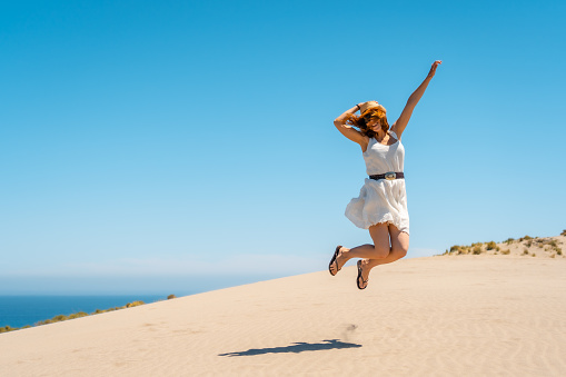 Happy woman jumping in a view point with sea views in Cabo de Gata, Spain