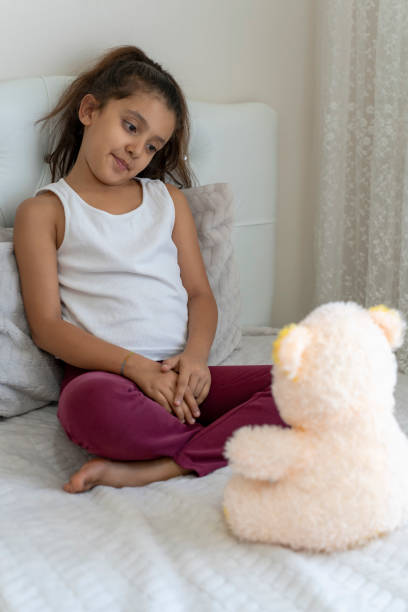 istock Girl playing with teddy bear in her room. 1824400590