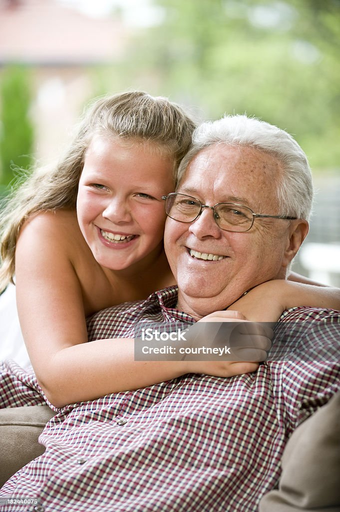 Senior hombre sonriendo ser hugged por su grandaughter - Foto de stock de Abrazar libre de derechos