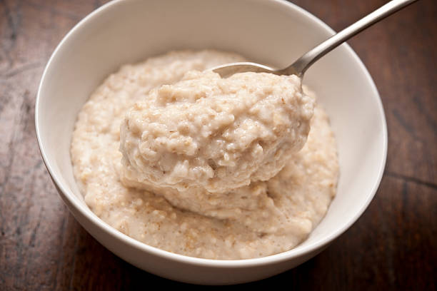 bowl of porridge bowl of Oatmeal ( Porridge ) from above with spoon. porridge stock pictures, royalty-free photos & images