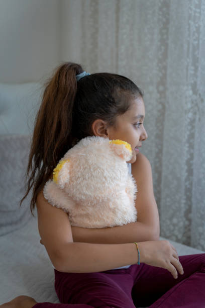 Girl playing with teddy bear in her room.