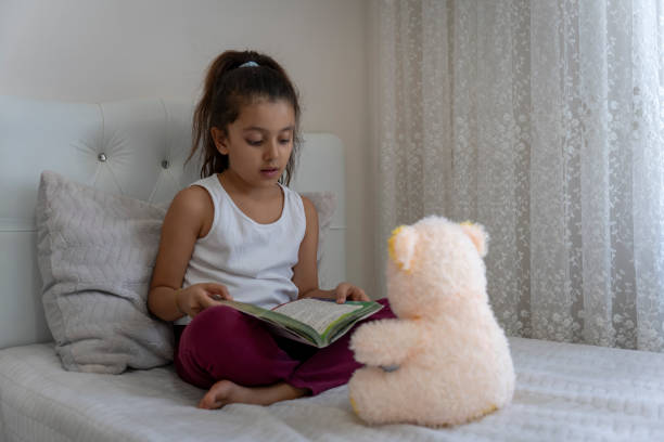 Girl playing with teddy bear in her room.