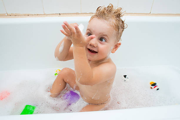 Baby girl playing in the bath stock photo