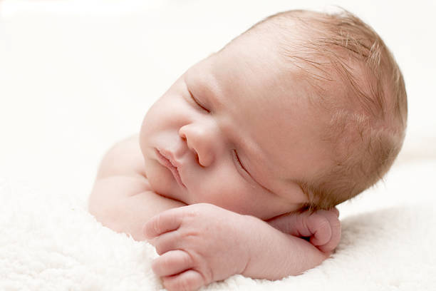 Sleeping newborn baby on a white towel stock photo