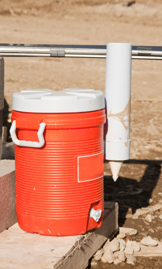an orange plastick water jug sits in the morning sun at the construction site
