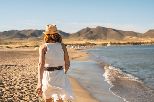 Rear view of a woman walking relaxed along the beach in Cabo de Gata, Spain