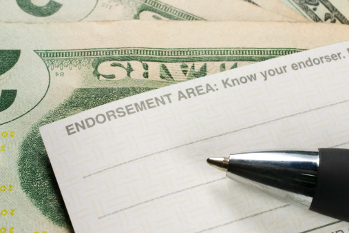 Endorsing the back of a check; Money is present under the check; Pen is slightly blurred.see related: