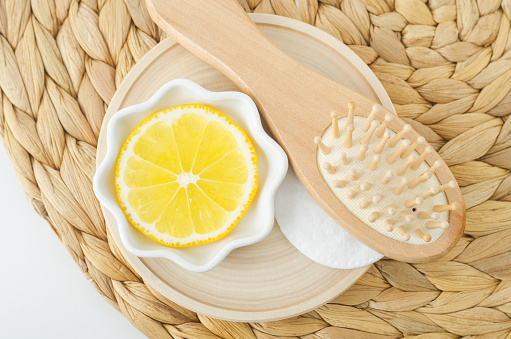 Lemon slice and wooden hairbrush for preparing homemade hair mask or diy hair dye. Natural beauty treatment and spa recipe.