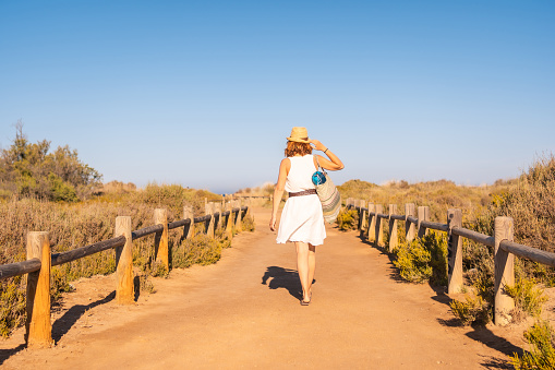 Rear view of a woman walking to the beach for a path in Cabo de Gata, Spain