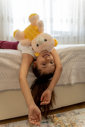 Girl playing with teddy bear in her room.
