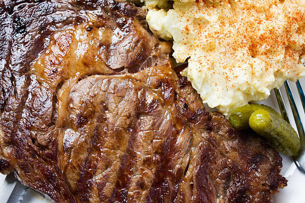 編み目のステーキ料理、ポテトのサラダとピクルス - rib eye steak steak beef prepared potato ストックフォトと画像