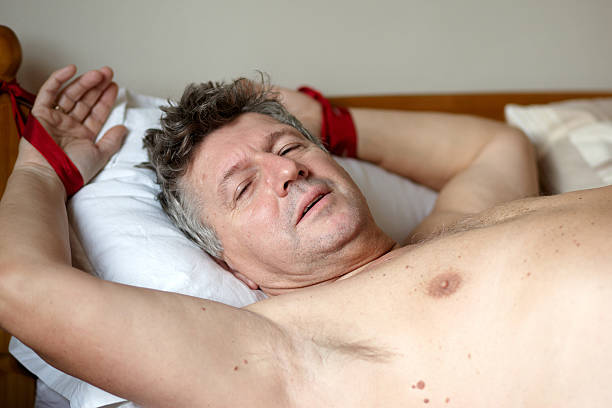 Mature man tied to bedpost Mature man tied to bedpost. man tied to bed stock pictures, royalty-free photos & images