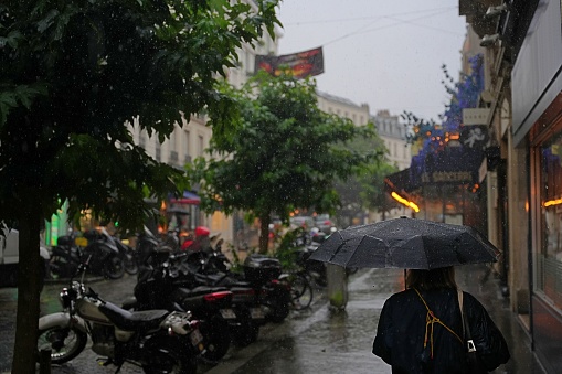 Paris, France - July 28, 2023: Pedestrian with umbrella in rainy Paris.