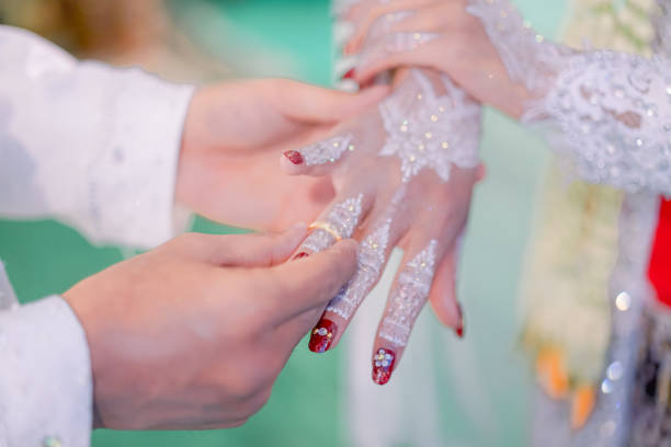 istock Wedding rings. He Put the Wedding Ring on Her. Close up Groom Put the Ring on bride. thai wedding ceremony and thai wedding decoration. Groom Put the Ring on bride's finger. 1824439123