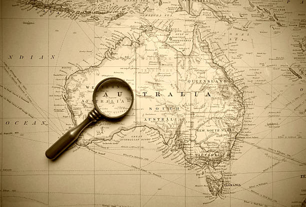 Vintage Map Of Australia A map from 1920 of Australia and its neighbours. An old brass magnifying glass lies upon it. new caledonia photos stock pictures, royalty-free photos & images