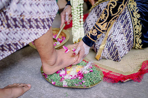Stampede Egg Ceremony in Javanese wedding. Groom breaks an egg using foot, signifies that he's ready to be a responsible head of family. The bride washes groom's foot as a symbol of support & loyalty.