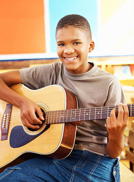afrikanische amerikanische schule junge spielt die akustische gitarre - elementary student school children child schoolboy stock-fotos und bilder