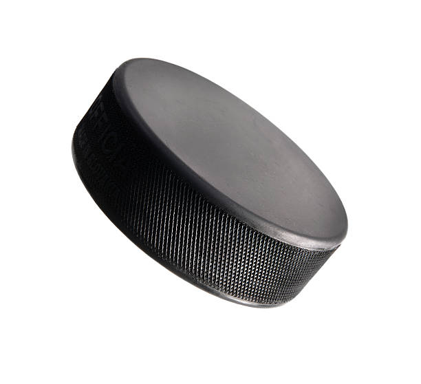 Best Hockey Puck On White "A studio shot of a well lit hockey puck standing on an angle, creates the look as though it is flying through the air. Gradated lighting amplifies the shape and curve of the puck. Click on an" hockey puck photos stock pictures, royalty-free photos & images