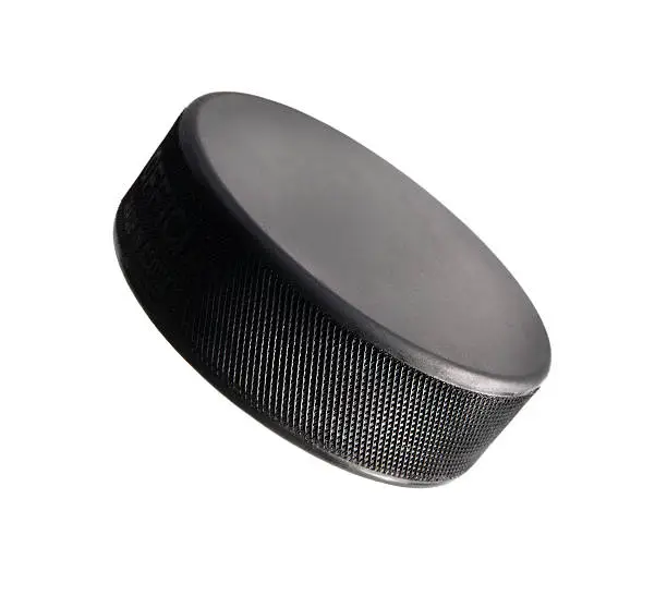 "A studio shot of a well lit hockey puck standing on an angle, creates the look as though it is flying through the air. Gradated lighting amplifies the shape and curve of the puck. Click on an"