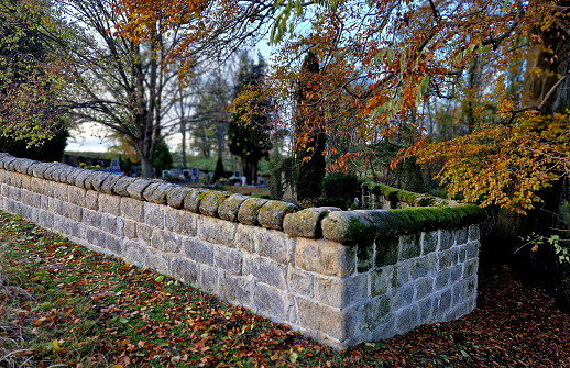 repaired renovated sandstone walls near the cemetery. stairs and railings of the wall made of new stone which weatheres quickly but is beautiful and beige from large easily workable blocks.  sloping, moss, graveyard