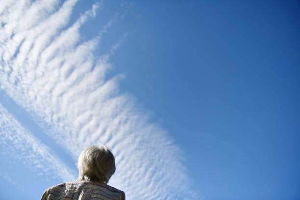 Senior woman looking at contrails in the blue sky