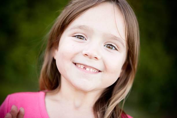 istock Happy Young Girl with Missing Tooth Smiling Outside 182445846