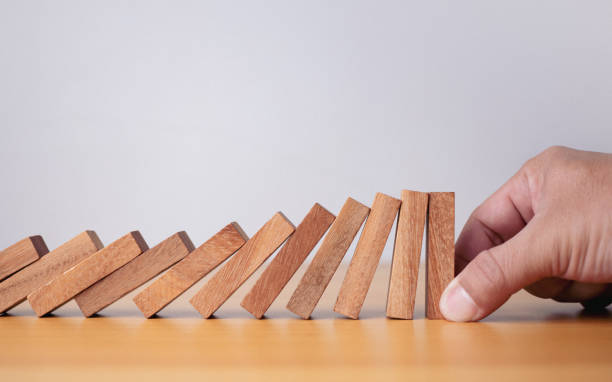 istock Businessman hand stopping falling blocks on table, stopping the domino effect concept for business solution, strategy and successful intervention. 1824476265