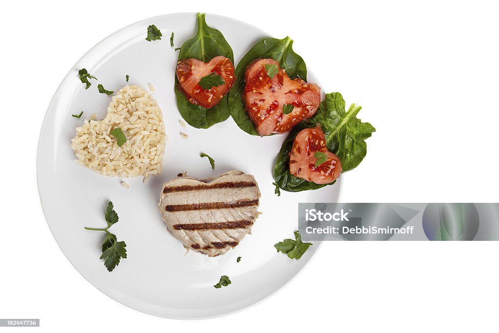 Heart Healthy Tuna Dinner "Grilled tuna, brown rice  and tomatoes on spinach all in heart shapes. Deliberate copy space left on right side." Brown Stock Photo