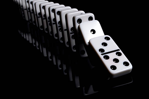Falling Dominoes "White dominos on a reflective, black background. Other images in this series:" domino stock pictures, royalty-free photos & images