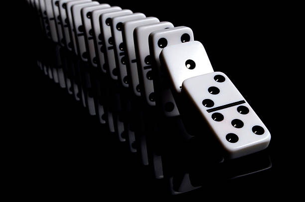 Falling Dominoes "White dominos on a reflective, black background. Other images in this series:" domino effect stock pictures, royalty-free photos & images