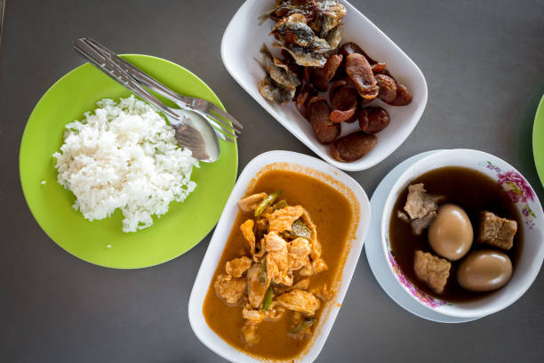Various of Thai meals such as pork panang curry, stewed eggs eating with rice on wood table. Top view