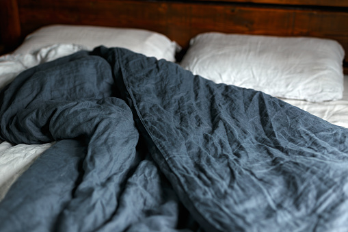 cosy Interior with white bed linen. Bedroom with oak bed, grey and blue bedding, and bedside table.