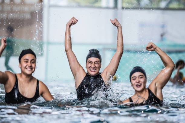 Portrait of water polo female players celebrating in the pool Portrait of water polo female players celebrating in the pool women exercising swimming pool young women stock pictures, royalty-free photos & images