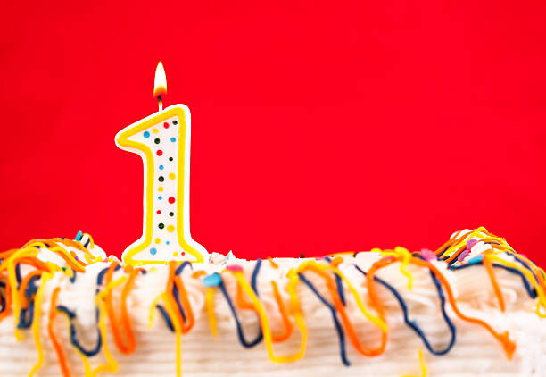 istock Decorated birthday cake with number 1 burning candle. Red background. 182455183