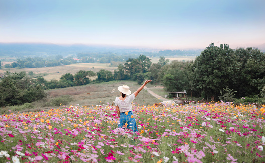 girl enjoying blooming flowers in garden watching at the high mountains in Thailand.