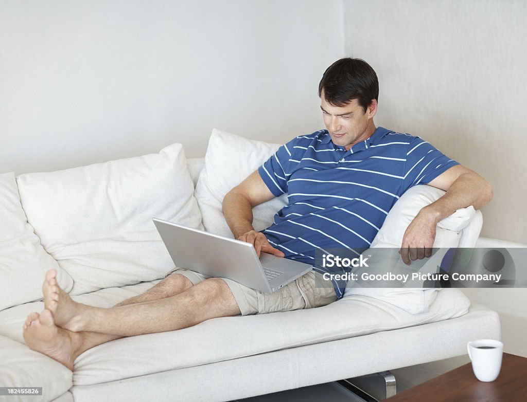 Homem maduro, usando um laptop enquanto relaxante no sofá - Royalty-free 40-44 anos Foto de stock