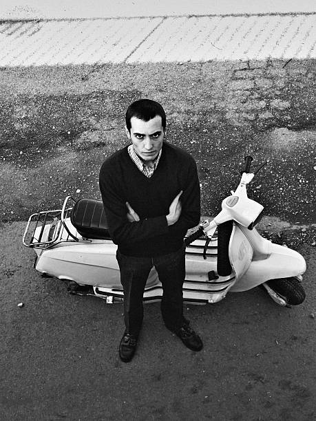 Young man with scooter Young mod with old scooter. Black and white with high contrast. Grain.Young mod. Black and white with high contrast. skin head stock pictures, royalty-free photos & images