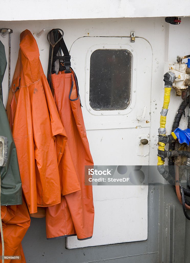 Commercial Fishing Boat Detail Detail shot of fishermanaas foul weather gear hanging next to the closed cabin door. Agriculture Stock Photo