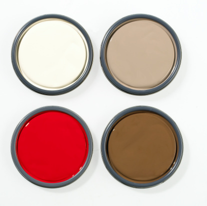 Overhead image of various coloured paint can lids photographed on a  white background.
