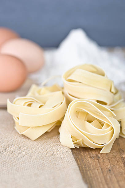 Fettucini pasta, eggs, flour, on wood & slate stock photo