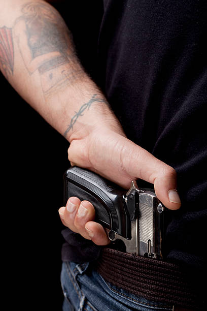tattooed sosteniendo una pistola brazo de borde interior de blue jeans. - tattoo gun fotografías e imágenes de stock