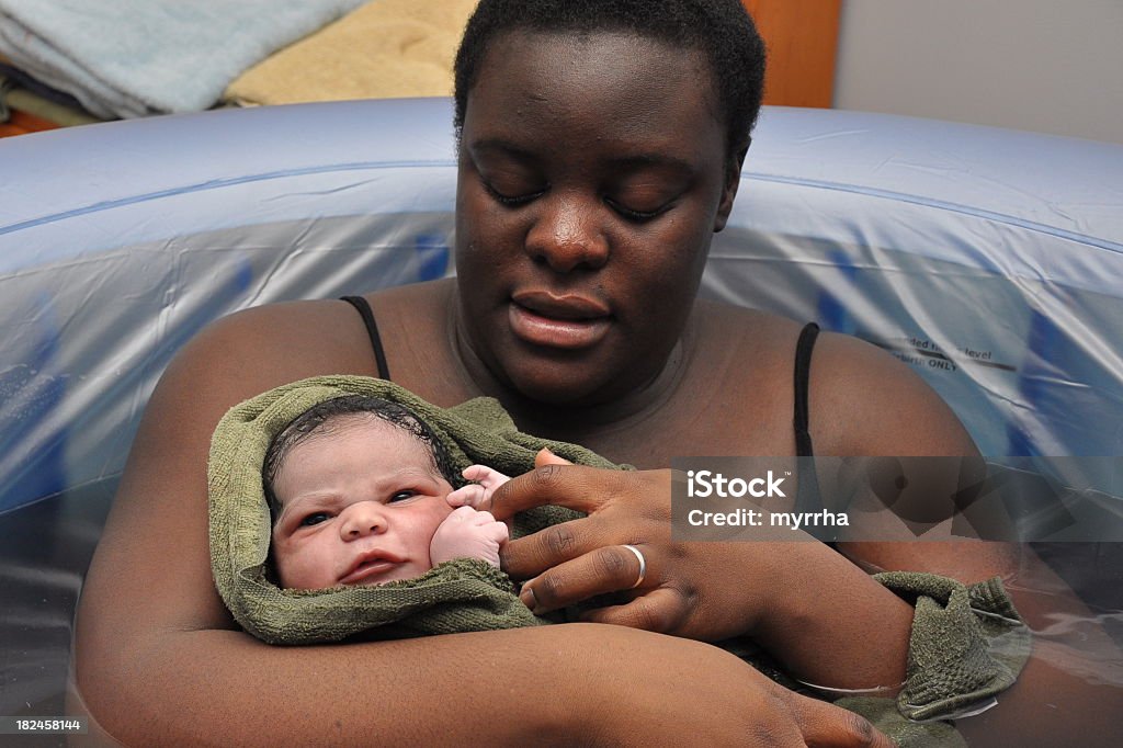 Baby Day~ Water Birth; newborn opens eyes mother cuddles baby freshly born Childbirth Stock Photo