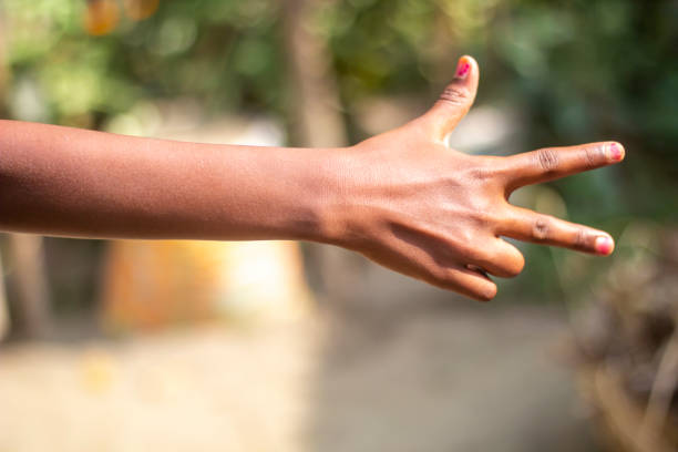 A man points his two fingers forward and the thumb of his hand pointing up and blurred background