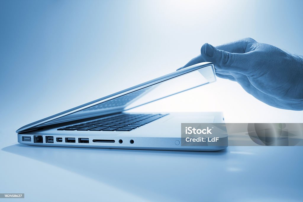 Hand opening a contemporary laptop computer Hand opening (or closing) a laptop screen.High Key with Soft Focus. Laptop Stock Photo