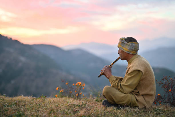 In this mesmerizing photo, a local Himachali man serenades the mountains, creating a symphony of tranquility as he plays a flute during the golden hues of sunset. The breathtaking Himalayan mountain range forms a majestic backdrop, its peaks bathed in the warm glow of the setting sun