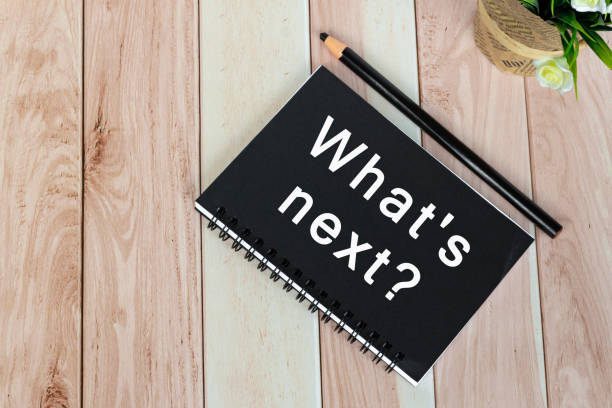 istock What's next? text on notepad on wooden desk with potted plant. 1824595206