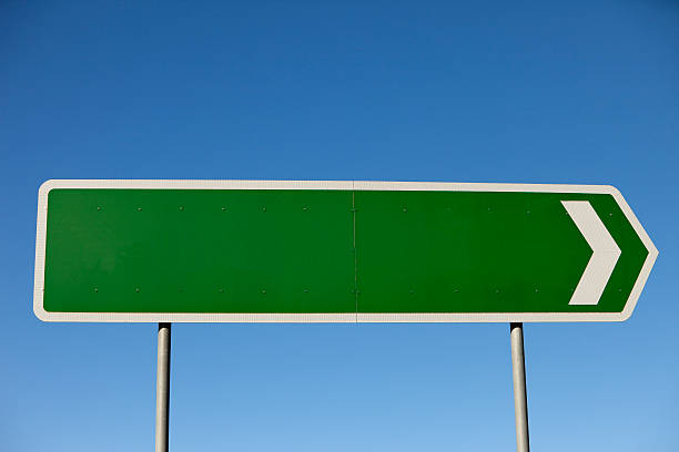 istock Blank road sign pointing to the right with blue sky 182460247