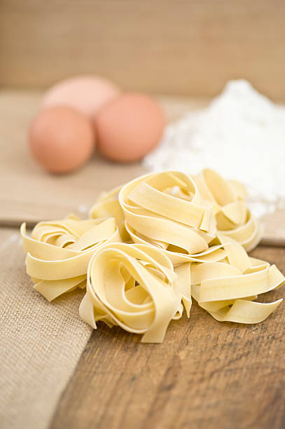 Fettucini pasta, eggs, flour on wood and sack cloth stock photo