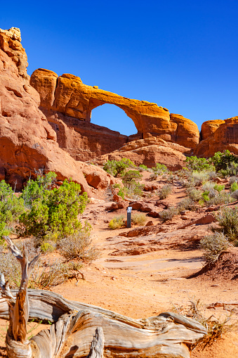 A woman walks through North Window Arch with Turret Arch in the background